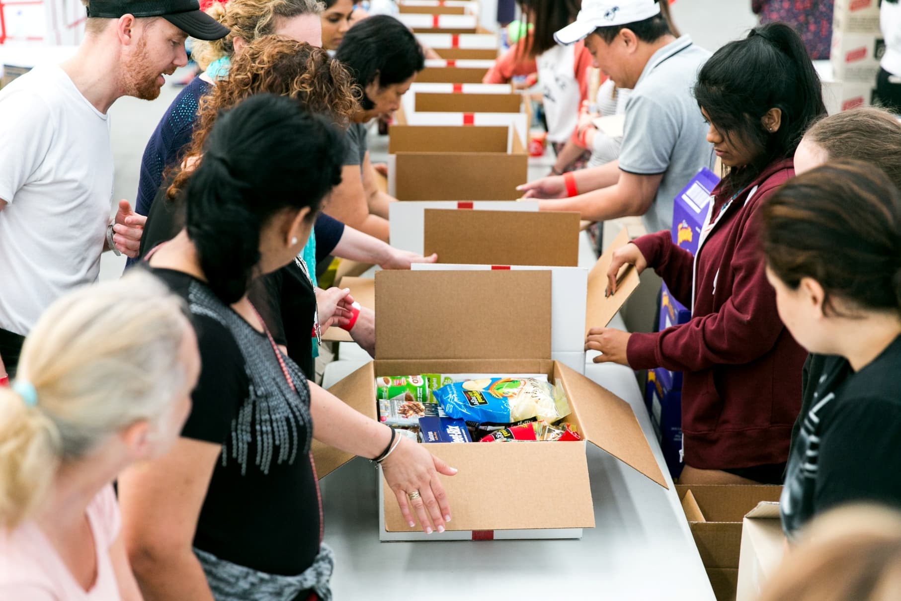 People helping at Christmas Box by packing boxes full of food.