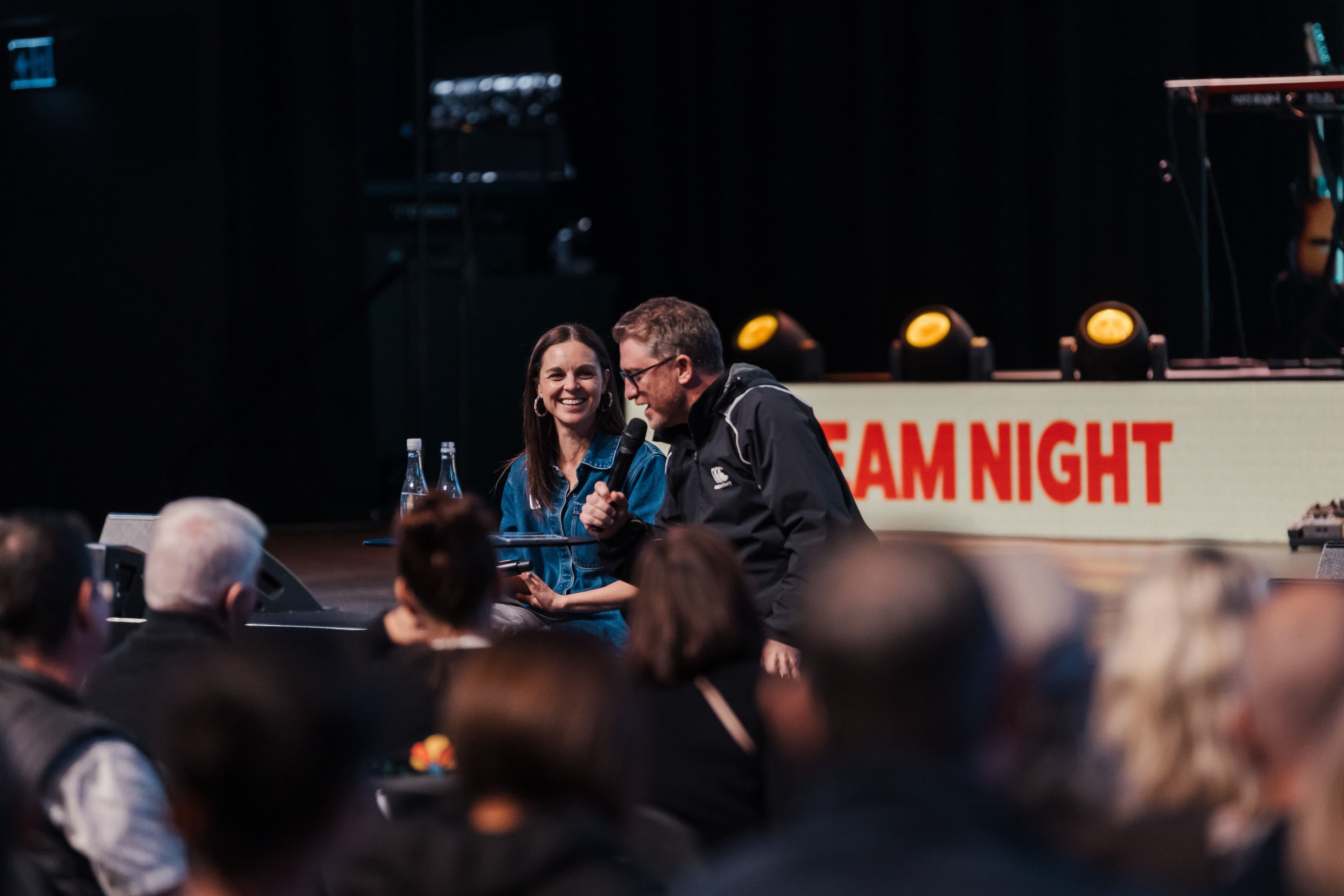 Two Campus Pastors sitting on the stage MCing Team Night