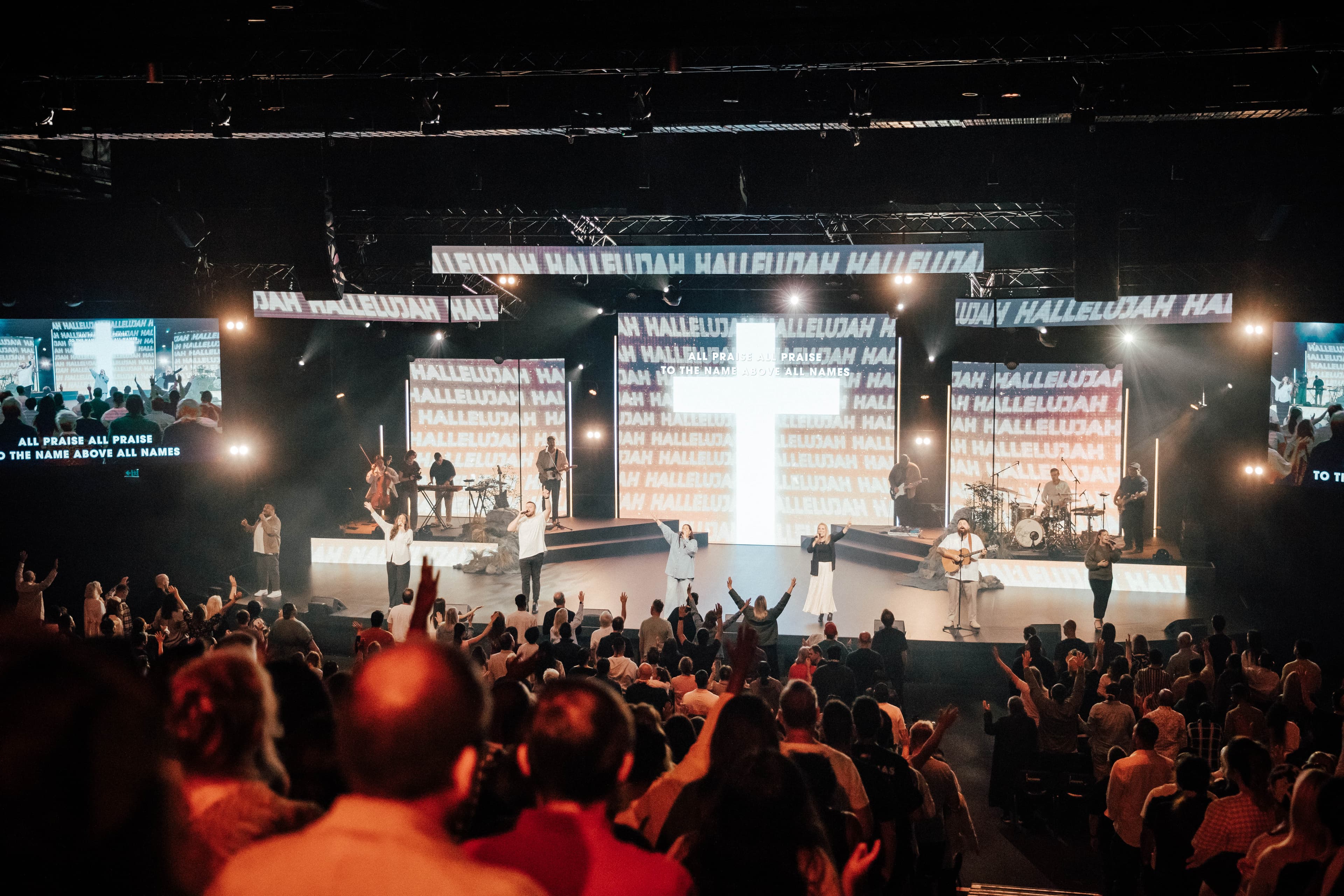 Looking at stage from up in the stands and there's a cross on the screen behind the worship team