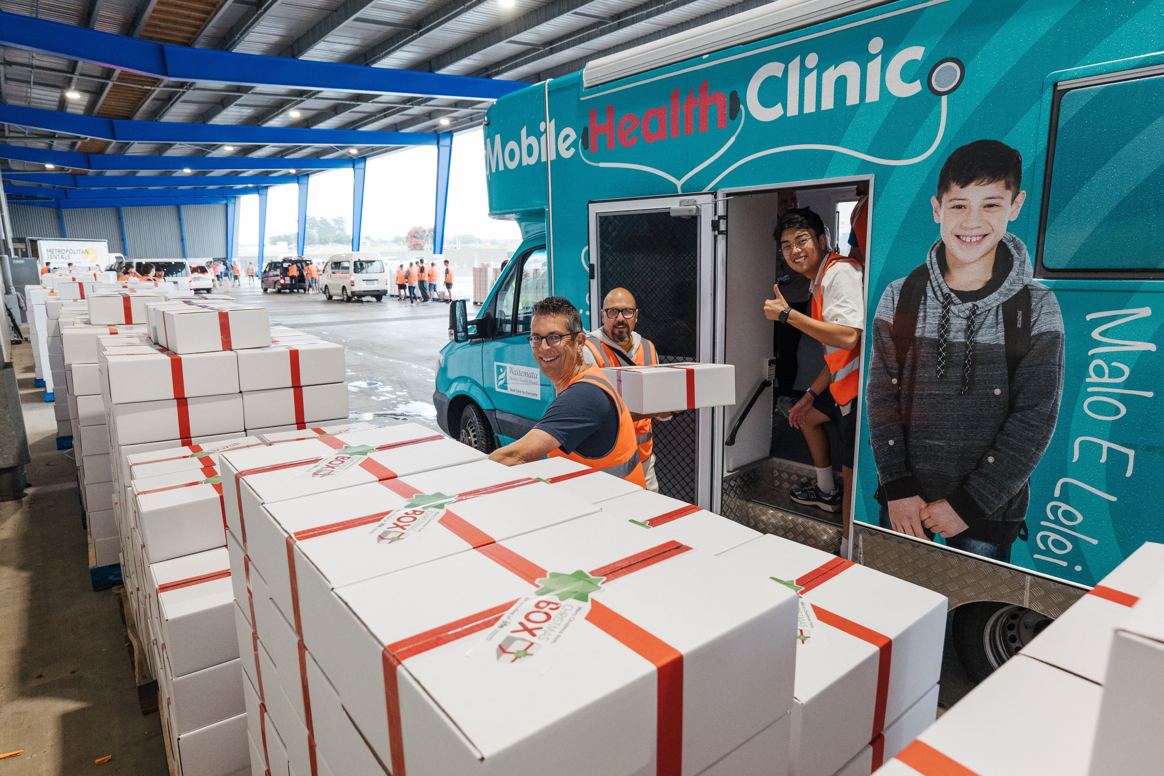 Stacks of Christmas Boxes being loaded into a community health clinic bus