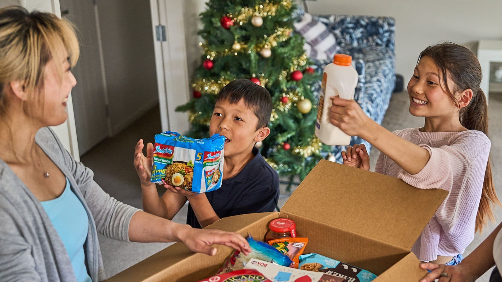 Two kids holding products they've pulled out of a Christmas Box with excited faces