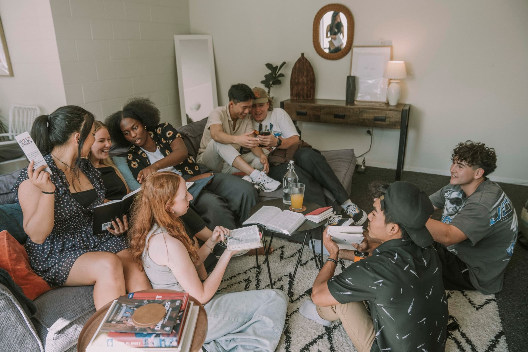 Young people sitting in a lounge chatting together with books, bibles, and pens in their Discipleship Group