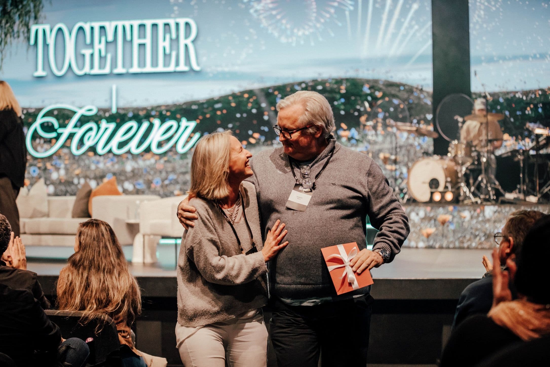 Couple with their arms around each other looking and smiling at each other after winning a competition at the Marriage Retreat at LIFE Central