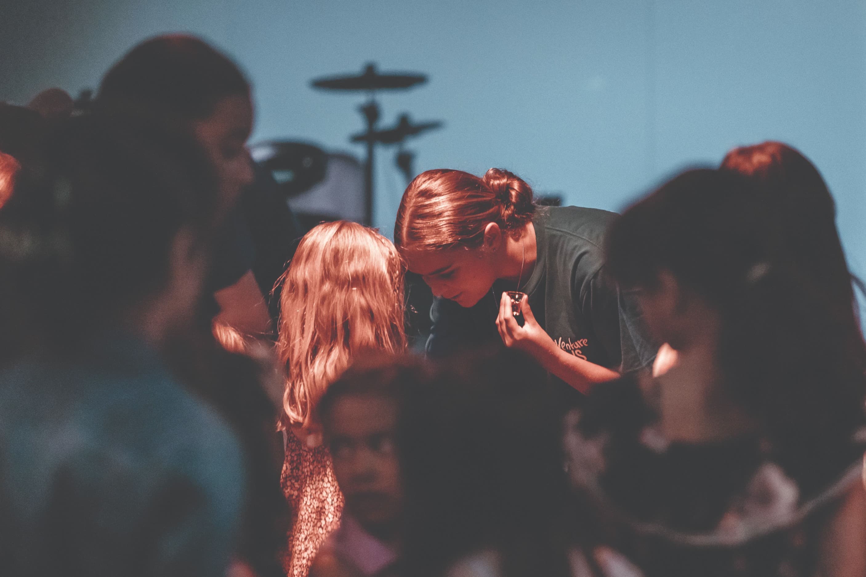 Adventure Kids leader bending down to a child and praying over them while holding anointing oil