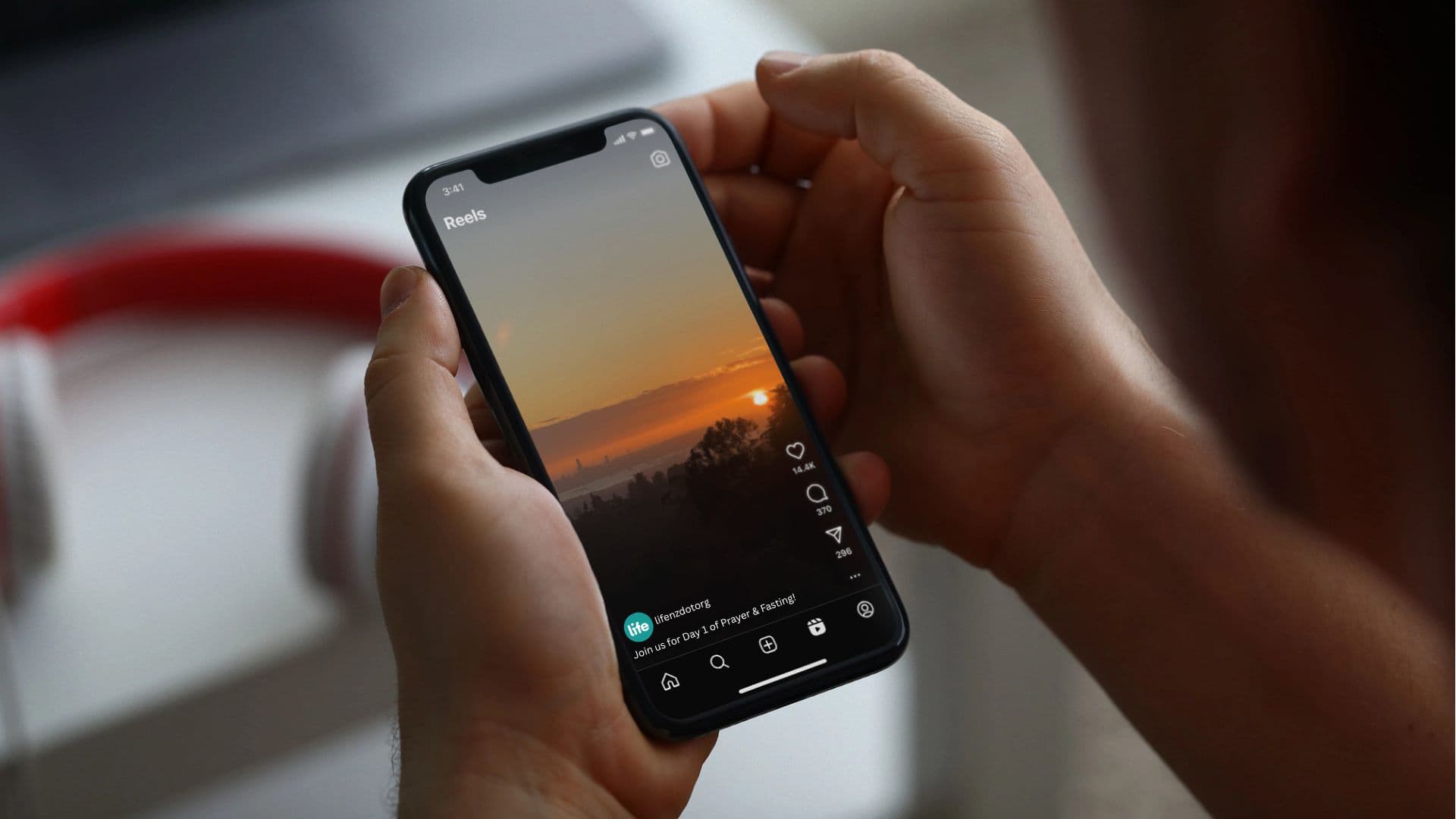 Hands holding a mobile phone with Instagram open showing a sunset