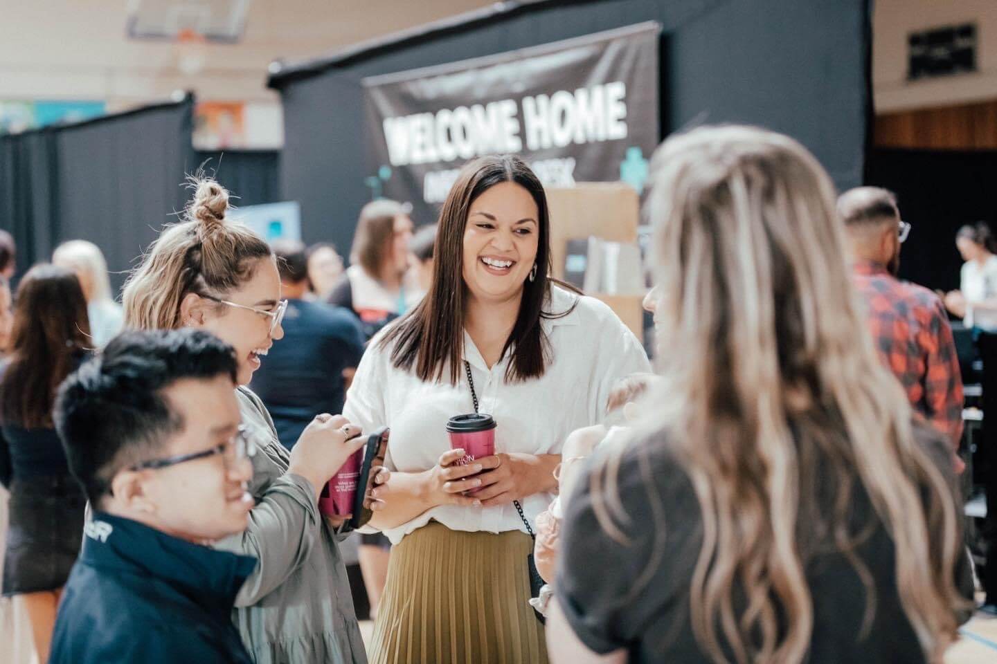 A group of people chatting out in the West Campus foyer